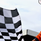 A photo of a marshal waving a black and white checkered flag at an F1 race.